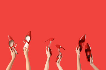 Female hands holding different shoes on red background - obrazy, fototapety, plakaty