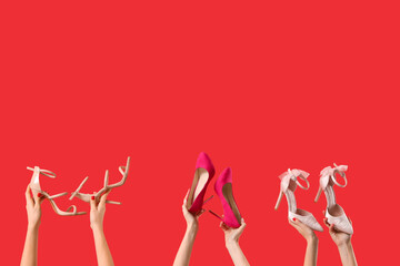 Female hands holding different shoes on red background