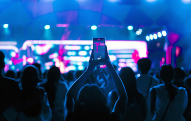 Girl holding smart phone and photographing in music festival concert, event background concept	
