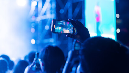 Girl holding smart phone and recording and photographing in music festival concert, party event...