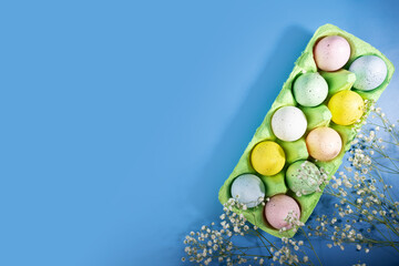 Obraz na płótnie Canvas Easter eggs in a box, spring flowers, blue background, celebration