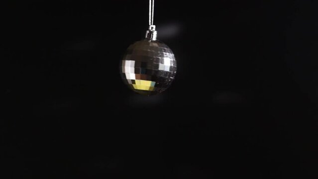 disco ball spinning, glitter shiny christmas decoration with sparkles and mirror reflections, dance floor, black background