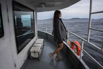 Istanbul. An Asian girl in a man's jacket is sailing on a ferry in Istanbul in cloudy weather,...