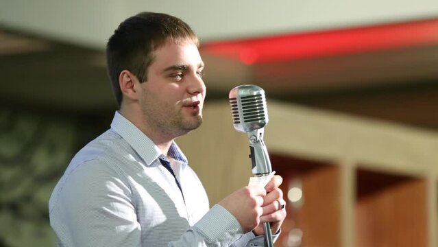 Young man speaks to microphone on competition of reciters