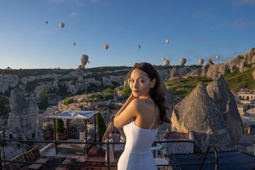 Fototapeta na wymiar Cappadocia, Asian woman watches the flight of hot air balloons early in the morning in Cappadocia, tourism in Turkey