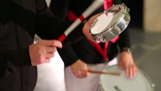 Male hands playing on small hand white drum on stage