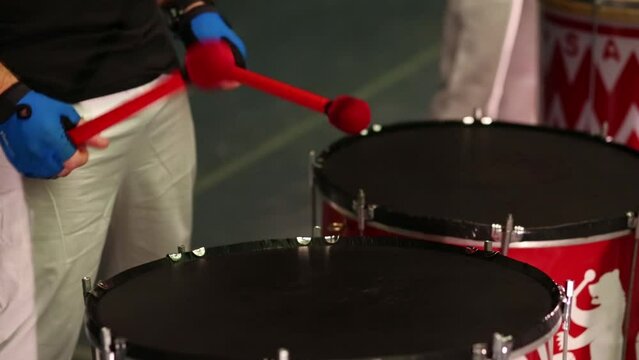 Male hands with red sticks playing on two big drums on stage