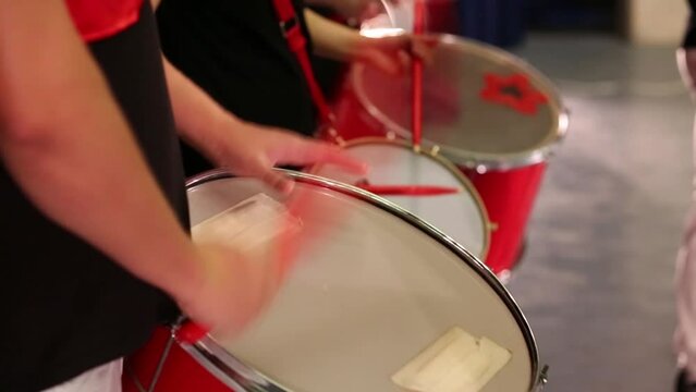 Hands of three musicians with sticks playing on drums on stage