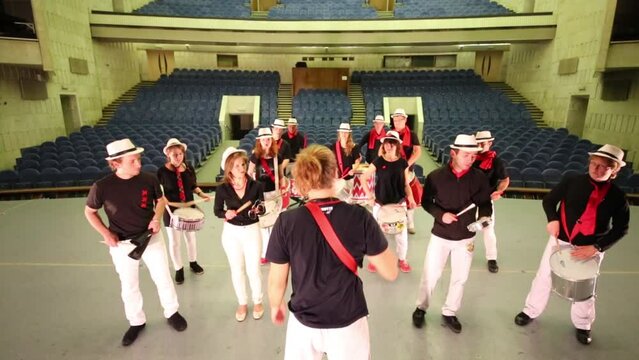 musical group of fourteen young people in hats playing drums