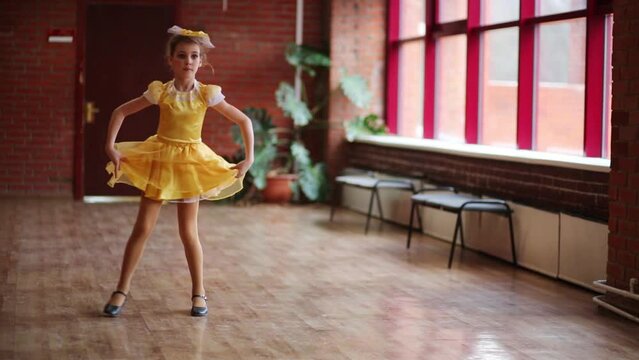 Girl in dress dancing next to the window in the spacious hall