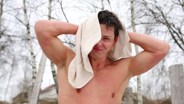 Handsome frozen man towel on the street near trees