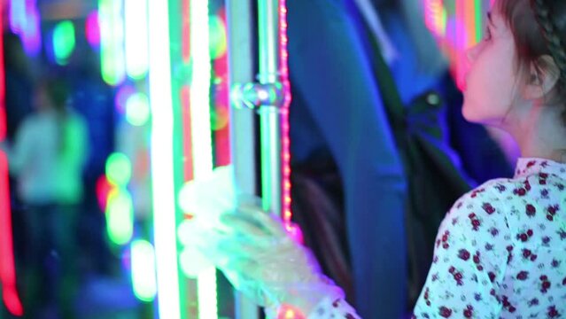 Little girl walks in mirror labyrinth illuminated 