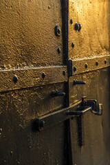 Old black metal door with lock hit by sunset light in Red Hook, Brooklyn, New York