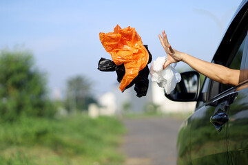 A young female driver throws rubbish from the car, plastic waste and bags. Environmental pollution, bad behavior on the road.