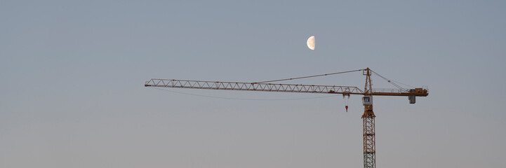 Crane and construction site against the blue sky. Working on large construction sites, and many cranes working in the new construction business.