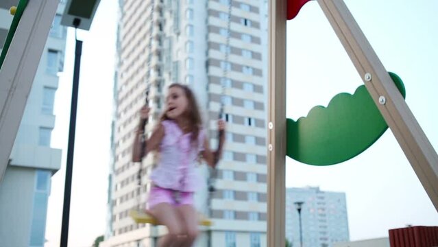 Little girl swings on swing at children playground
