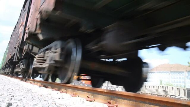 Wheels of big fast moving freight train on railway at summer day