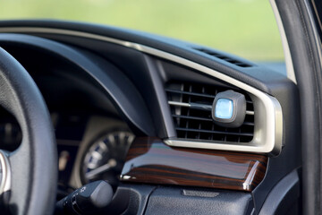 The female driver's hand puts car perfume on the AC grill. perfume packaged in bottles and wooden caps. car air freshener.