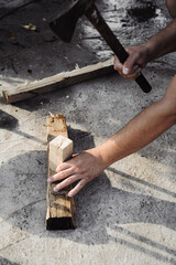 A man chops wood with an ax to light a fire. Backyard work.
