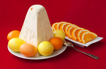 Traditional Easter cottage cheese dessert Paskha with eggs and oranges on red background. Modern...