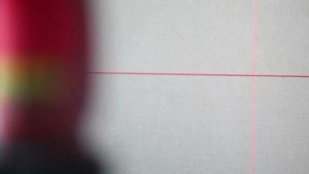 Red laser markings line on concrete wall, thread and worker hand