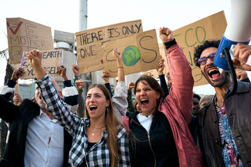 Serious girl with her fist in the air in a demonstration. Group of people at manifestation on...
