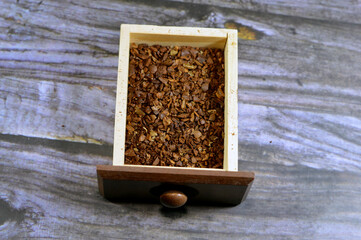 a wood drawer with coffee inside it from a manual coffee grinder burr mill machine with catch...