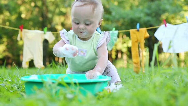 Baby touches and eats foam in basin on grass