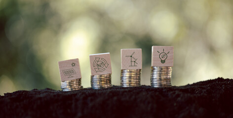 Green energy icons on wooden cubes with stack money coin. Green business growth. Finance...