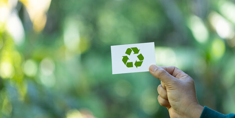 eco living, environment and sustainability concept. Hand holding recycle symbol on green bokeh...