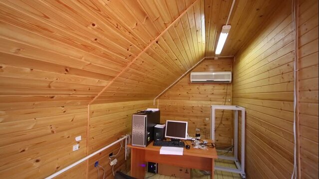 A small room in the attic decorated in wood with a work desk