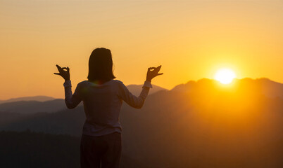 Panorama back view of woman is relaxingly practicing meditation yoga at top of mountain with rising...