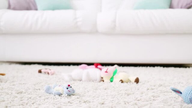 Knitted soft toys lie on thick fluffy white carpet next to sofa