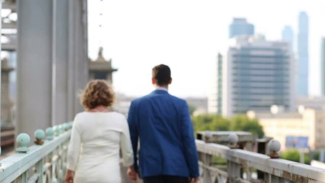 Back of pregnant woman and man walking together on railway bridge