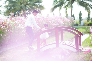 Little girl with her father on nature background A back view of the Father in Heaven concept. Father holds daughter's hand as she walks.