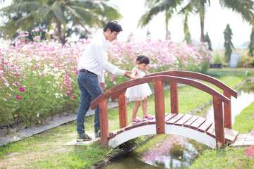 Little girl with her father on nature background A back view of the Father in Heaven concept. Father holds daughter's hand as she walks.