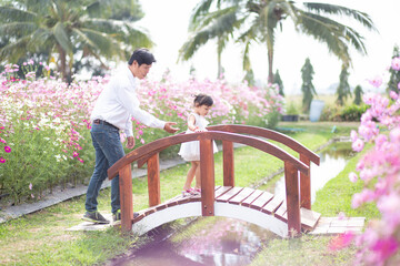 Little girl with her father on nature background A back view of the Father in Heaven concept. Father holds daughter's hand as she walks.