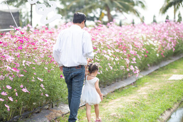 Little girl with her father on nature background A back view of the Father in Heaven concept. Father holds daughter's hand as she walks.