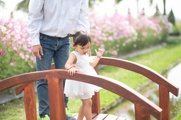 Little girl with her father on nature background A back view of the Father in Heaven concept. Father holds daughter's hand as she walks.
