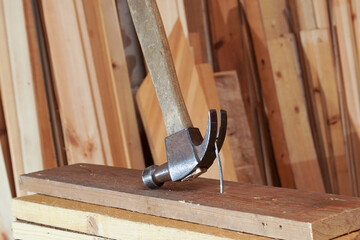 A carpenter's hammer and a nail being pulled out of a board.