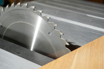 Close-up of a circular saw blade ready to go and a board.
