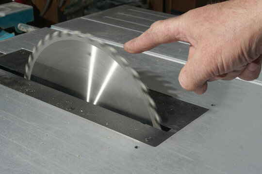 The index finger points to the rotating circular saw blade. Injury safety concept.