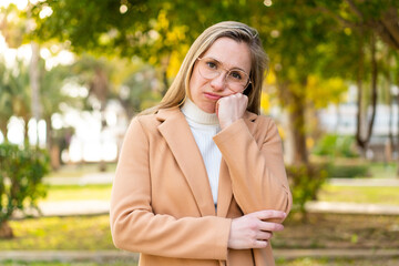 Young blonde woman at outdoors With glasses and with sad expression