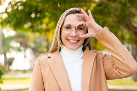 Young blonde woman at outdoors With glasses with happy expression