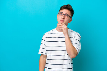 Young handsome Brazilian man isolated on blue background having doubts