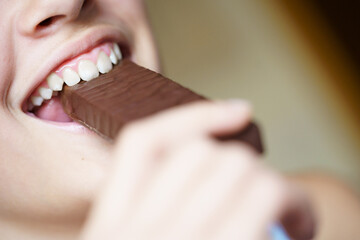 Happy crop anonymous teenage girl biting nutritious protein bar