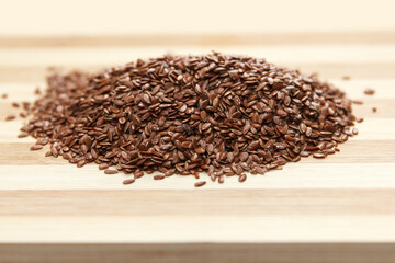 Many linen raw seeds lie on a wooden surface, prepared for use in cooking