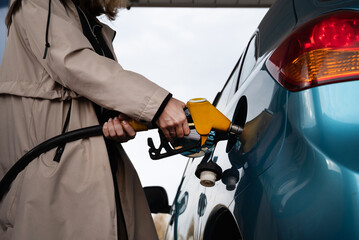 Pumping gas at the gas pump. The woman refuels the car. A woman at a gas station. A woman refuels a...