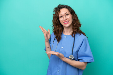 Young nurse caucasian woman isolated on blue background extending hands to the side for inviting to...