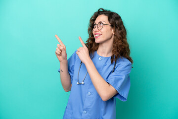 Young nurse caucasian woman isolated on blue background pointing with the index finger a great idea - obrazy, fototapety, plakaty